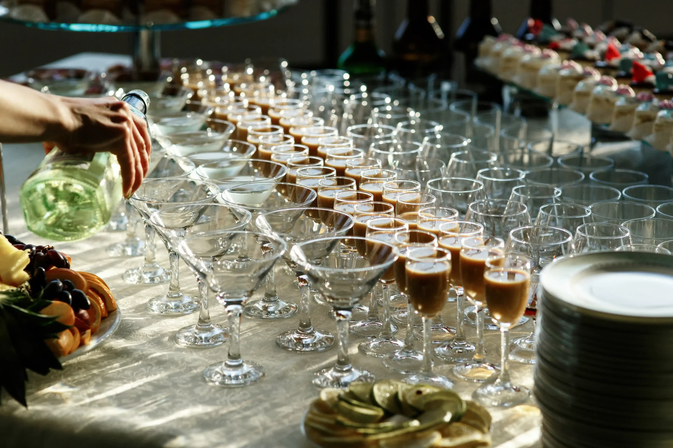 man-pours-martini-cocktail-glasses-dinner-table